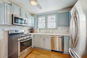 A kitchen with stainless steel appliances, white cabinets, and a wooden floor. - 2nd-Floor Apartment w/Balcony, Partial AC, Shared Gas Grill, Washer/Dryer (Ocean City)