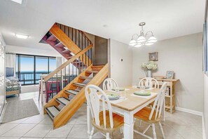 Ein Essbereich mit einer Holztreppe, weißen Stühlen und einem Tisch für vier Personen.