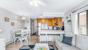 A modern living room with a sofa, coffee table, and dining area. - Condesa 201 (Ocean City)