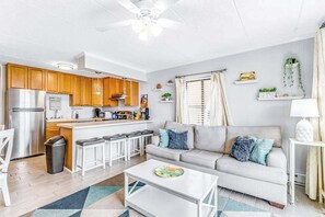 A compact living space with a kitchenette, a sofa, a coffee table, and a dining area. - Bright, sunny condo with ocean and bay views in walkable Midtown location (Ocean City)
