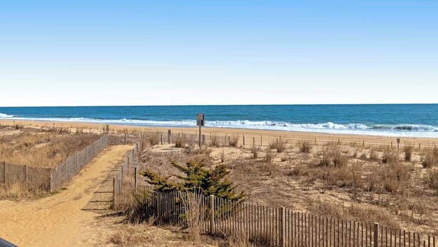 A beach with a wooden fence, a sandy path, and the ocean in the background. - Condesa 201 (Ocean City)