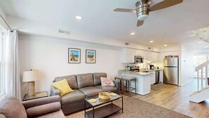 A modern living room with a sofa, coffee table, and kitchen in the background. - Bay Island 4 (Ocean City)