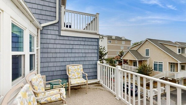 A residential building with a balcony, a chair, and a small table. - Oceanfront Townhome w/ Multi-Level Decks, Great View, W/D & Beach Access (Ocean City)