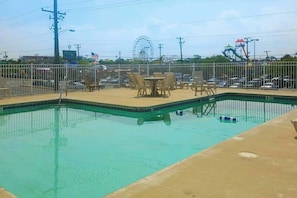 A swimming pool with a green border, surrounded by a white fence. - Comfortable studio with outdoor pool - walk to the beach (Ocean City)