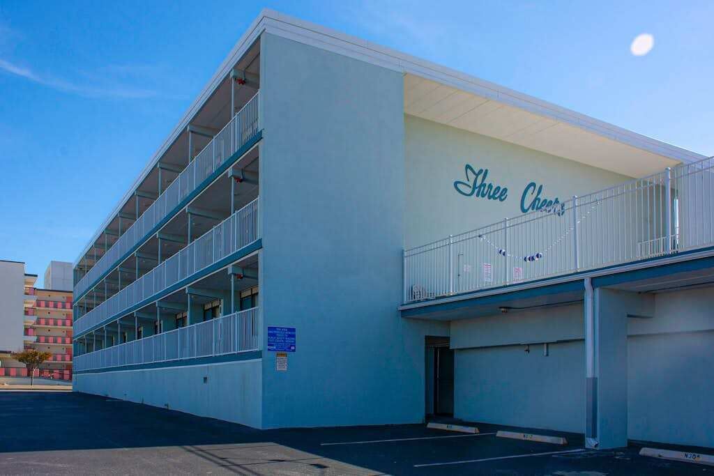 Un bâtiment sur lequel on peut lire l’inscription « Three Cheers » et qui dispose d’un espace de stationnement couvert.