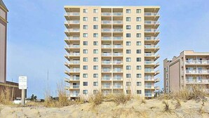 Ett hotell med flera våningar och balkonger, beläget nära en sandstrand.