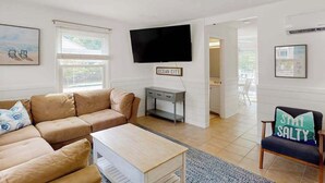Olohuoneessa on beige sohva, sohvapöytä, televisio ja kyltti, jossa lukee ”OCEAN CITY”.