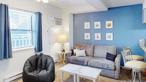 Ein Wohnzimmer mit Sofa, Couchtisch, Sitzsack, Deckenventilator, Lampe und Kunstwerken an der Wand.