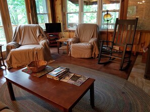 A cozy living room with two armchairs, a wooden coffee table, a television, and a rocking chair.