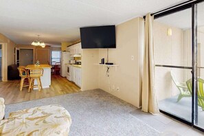 A living room with a flat-screen TV, a dining area with a table and chairs, and a sliding glass door leading to a balcony. - Sea Terrace 803 | Condo in Ocean City (Ocean City)