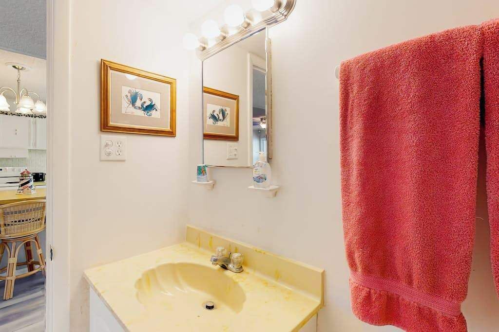 Een badkamer met een wastafel, spiegel en handdoekhouder.
