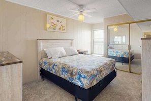 A bedroom with a bed, a ceiling fan, a bedside table, and a mirror. - Sea Terrace 803 | Condo in Ocean City (Ocean City)