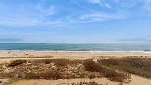 Ein Strand mit einer Umzäunung, Sanddünen und dem Meer.