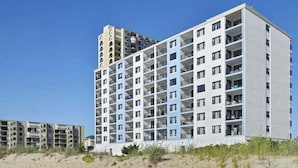 Un hôtel à plusieurs étages, doté de balcons, d’un toit plat et surplombant un ciel dégagé.