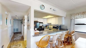 Une cuisine avec un îlot central, des chaises en bois et une horloge au mur.