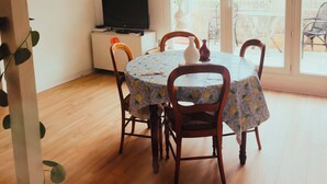 Un espace repas comprenant une table, des chaises, un téléviseur et un climatiseur.