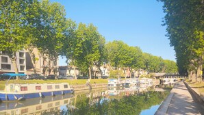 Un canal bordé de bateaux, d’arbres et d’un sentier.