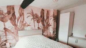 Une chambre à coucher comprenant un lit, une table de chevet, une armoire et une fresque murale.