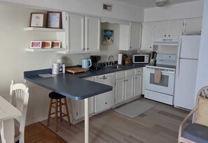 Una cucina con mobili bianchi, un piano di lavoro blu, una macchina da caffè, un forno a microonde e un fornello.