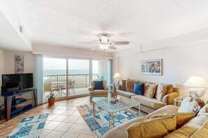 A living room with a television, sofa, coffee table, and a balcony with a view. - High Point South 4F (Ocean City)