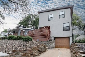 Ein modernes, zweistöckiges Haus mit Garage, einer Mauer aus Naturstein und einer Holzterrasse.