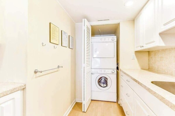 A compact laundry room with a washing machine, dryer, and a small sink. - 81 Beach Hill 411 (Ocean City)