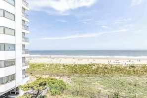 Ein Hotel direkt am Strand mit Blick auf den Ozean, einem Sandstrand und einer Dünenlandschaft.