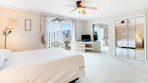Ein Hotelzimmer mit Bett, Schreibtisch, Fernseher, Deckenventilator und Schiebetürenschrank.
