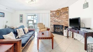 Ein Wohnzimmer mit einer Couch, einem Couchtisch, einem Fernseher, einem Kamin und einer Ziegelwand.