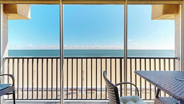 En balkon med udsigt over havet, et bord og to stole.