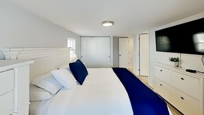 Une chambre d’hôtel avec un lit, une télévision, une commode et un placard.