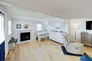 A living room with a fireplace, a sofa, a TV, and a dining table. - Montego Bay Charmer with 2 Pools, Tennis & Putt-Putt - Walk to Beaches (Ocean City)