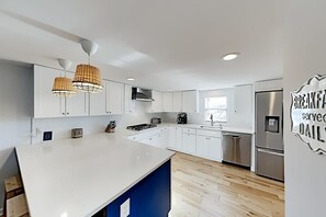 A modern kitchen with white cabinets, a large island, stainless steel appliances, and pendant lighting. - Montego Bay Charmer with 2 Pools, Tennis & Putt-Putt - Walk to Beaches (Ocean City)