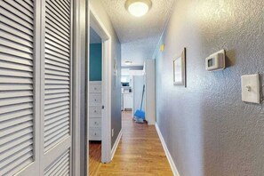 Ein Flur mit Holzboden, Deckenleuchte und einer Tür mit Jalousien.