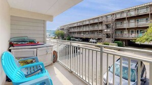 A balcony with a view of a multi-story building, a car parked below, and a blue chair. - Completely remodeled condo with private balcony - 100 yards to beach (Ocean City)