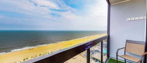A balcony with a view of the beach and pool area.
