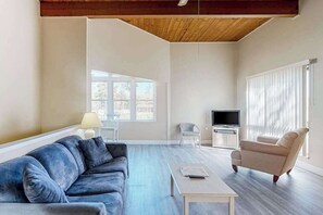 A living room with a sofa, armchair, TV, and a table.