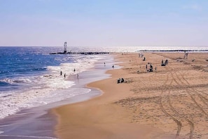 A beach with people, a lighthouse, and a clear sky. - Large two-level home with two kitchens, two decks, fast WiFi, & great location (Ocean City)