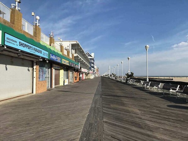 Une promenade en bord de mer bordée de boutiques, un ciel dégagé et une vue sur l’eau.