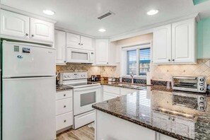 A kitchen with white cabinets, a refrigerator, a stove, a microwave, a sink, and a toaster. - Blue Sea Colony 202 (Ocean City)