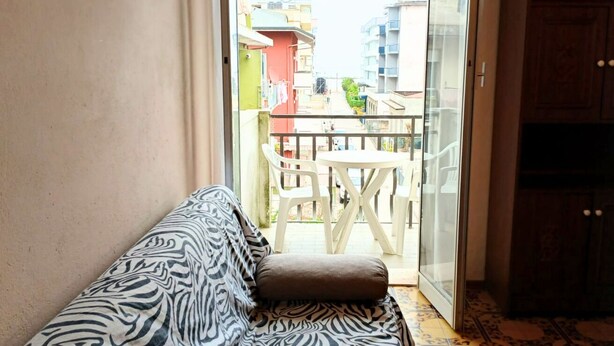 Un balcon aménagé avec un canapé, une table et des chaises, donnant sur un quartier résidentiel.