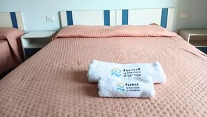 Une chambre d’hôtel avec un lit, une table de chevet et un interrupteur fixé au mur.