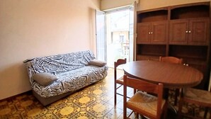 Un salon avec un canapé à motifs zébrés, une table de salle à manger ronde en bois, accompagnée de chaises, et un meuble avec des portes.