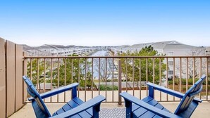 Ein Balkon mit blauen Stühlen, Blick auf eine Wohngegend und einen klaren Himmel.