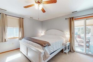 Ein Schlafzimmer mit Bett, Nachttisch, Deckenventilator und Blick ins Freie.