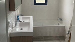 A modern bathroom with a large window, a bathtub, a sink, and a mirror. - Villa des amis (Caissargues)