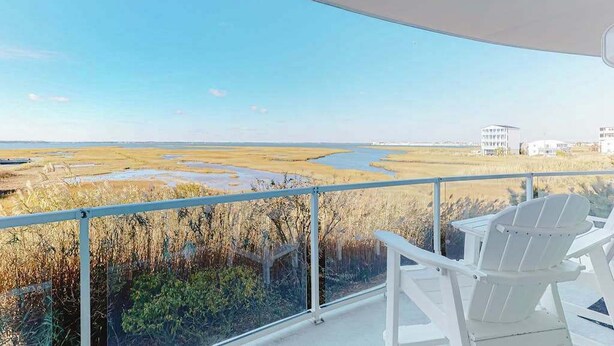Ein Balkon mit Blick auf eine sumpfige Landschaft und Gebäude in der Ferne.