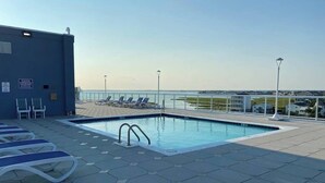 Ein Pool auf dem Dach mit Liegestühlen und freiem Blick auf die Skyline der Stadt.