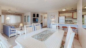 Un salon comprenant une table à manger, des chaises, un canapé, un téléviseur et un ventilateur de plafond.