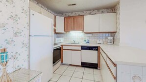 Une cuisine de taille réduite avec des meubles blancs, un four à micro-ondes, un évier et un lave-vaisselle.